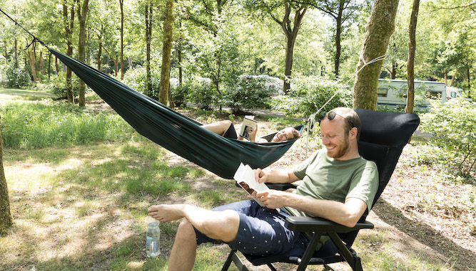 stel geniet op Natuurkampeerterrein van lezen in een hangmat