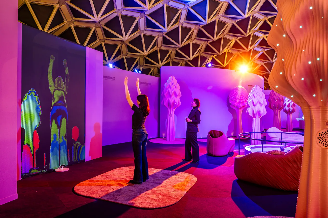 A visitor raising her arms in a purple-lit room of the Digital Wellness Centre